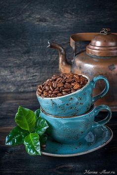 two tea cups and saucers filled with coffee beans