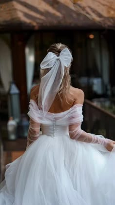 a woman in a white wedding dress is walking down the stairs with her veil over her head