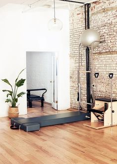 an empty room with wooden floors and brick walls, including a yoga mat on the floor