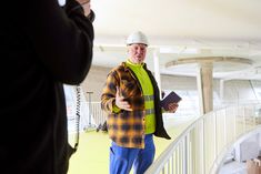 a man wearing a hard hat standing on top of a balcony next to another man