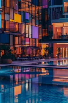 an empty swimming pool in front of a multi - story building at night with lights reflecting off the windows