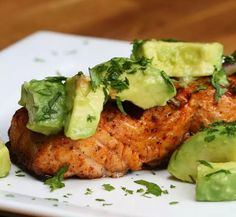 a white plate topped with meat covered in avocado