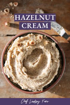 a bowl filled with hummus and nuts on top of a wooden table