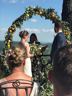 a bride and groom are getting married under an orange tree at their outdoor wedding ceremony