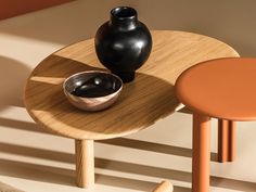 two black vases sitting on top of a wooden table next to an orange stool