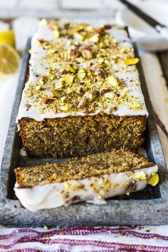 there is a loaf of cake with white frosting and nuts on it, next to two slices of bread