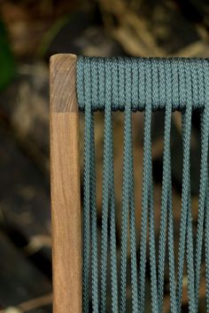 a close up of a wooden chair with blue rope on it