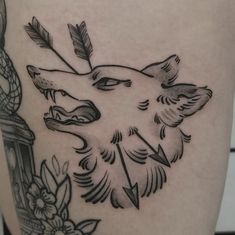 a black and white tattoo of a wolf with feathers on it's back leg