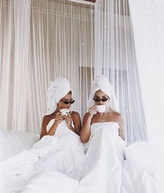 two women in white robes sitting on a bed