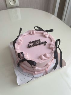 a pink birthday cake sitting on top of a white table