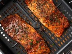 two pieces of meat sitting on top of a grill grate with seasoning sprinkles