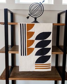 a quilt hanging on a shelf in a room with wooden shelves and shelving units