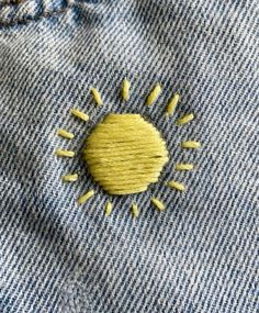 a yellow pin sitting on the back of a pair of blue jeans with holes in it