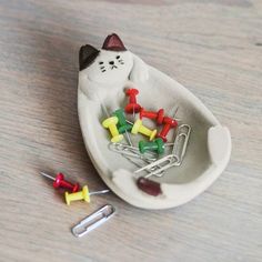 a cat pin cushion with pins in it