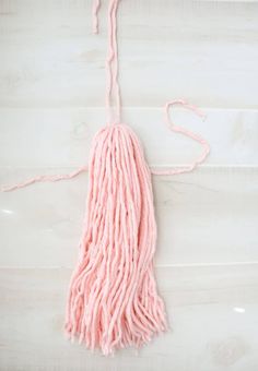 a pink mop laying on top of a white wooden floor next to a pair of scissors