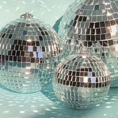 three shiny disco ball ornaments sitting on top of a blue surface with snow flakes