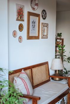 a wooden bench sitting next to a white wall with pictures on the wall above it