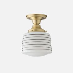 a white and gold light fixture on a gray background with no one in the photo