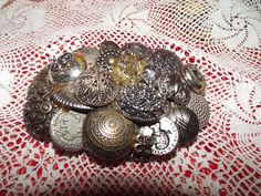 a bunch of buttons sitting on top of a lace covered table cloth next to a red and white doily