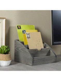 a desk with a computer monitor, potted plant and post it notes on the shelf