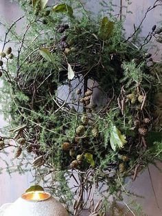 a wreath is hanging on the wall next to two vases with plants in them