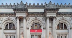 an ornate building with columns and arches on the front door, has a red sign that reads