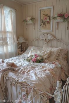 a white bed sitting in a bedroom next to a window filled with curtains and flowers