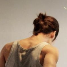 a woman in grey tank top flying a white frisbee with her back to the camera