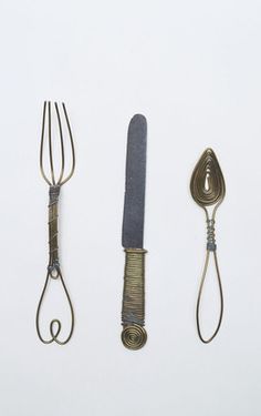 three different types of kitchen utensils on a white surface with wire wrapped around them