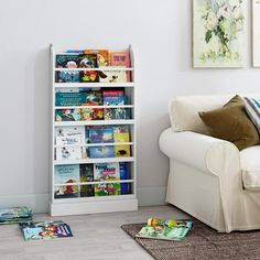 a white couch sitting next to a book shelf filled with books