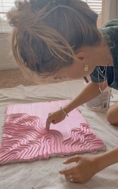 a woman is painting a piece of art on the floor