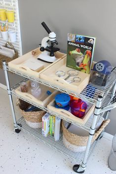 a metal cart with two bins on top of it next to a book shelf