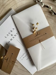 the wedding stationery is wrapped in white paper and tied with twine gold pins