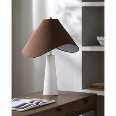 a table lamp sitting on top of a wooden desk next to a book shelf and window