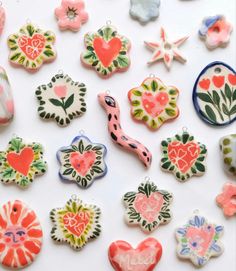 various ceramic ornaments are displayed on a white surface with flowers and hearts in the center