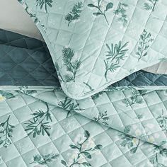 the comforter is made up with green and white flowers on it, along with two pillows