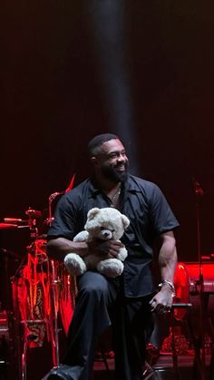 a man holding a teddy bear on stage