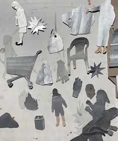 an assortment of paper cut outs on top of a piece of cardboard with people standing around them