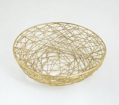 a gold wire basket sitting on top of a white table