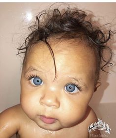 a close up of a baby's face with blue eyes and hair in the bathtub