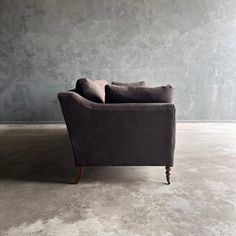 a couch sitting on top of a cement floor in front of a wall with grey walls