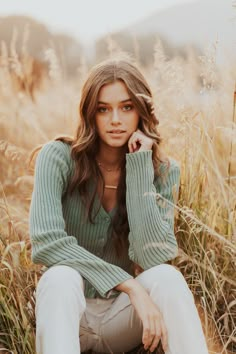 a beautiful young woman sitting in tall grass