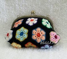 a black purse with crocheted flowers on the front and bottom, sitting on a white surface