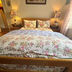 a bed with floral comforter and two lamps on either side of the headboard