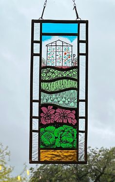 a stained glass window hanging from the side of a building with trees in the background