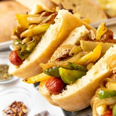 two hot dogs with peppers, onions and mustard on a tray next to some bread