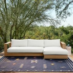 a couch sitting on top of a blue rug in front of a tree filled forest