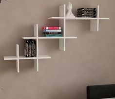 three white shelves with books on them against a gray wall next to a black chair