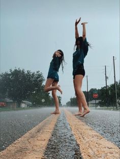 two girls jumping in the air on an asphalt road