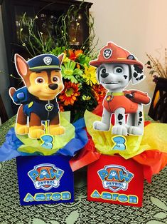 three paper bags with paw patrol characters on them sitting on a table next to a bouquet of flowers